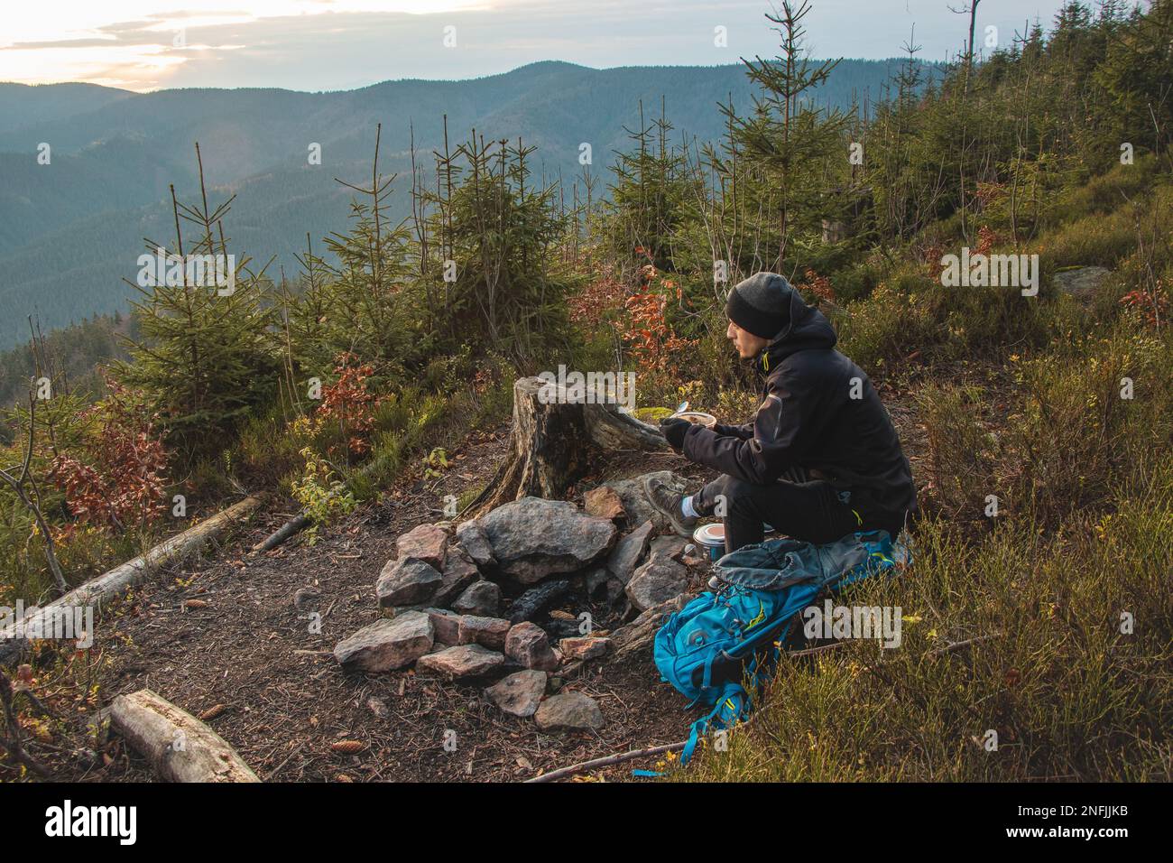 Outdoor wilderness trekking enthusiast sitting by a campfire