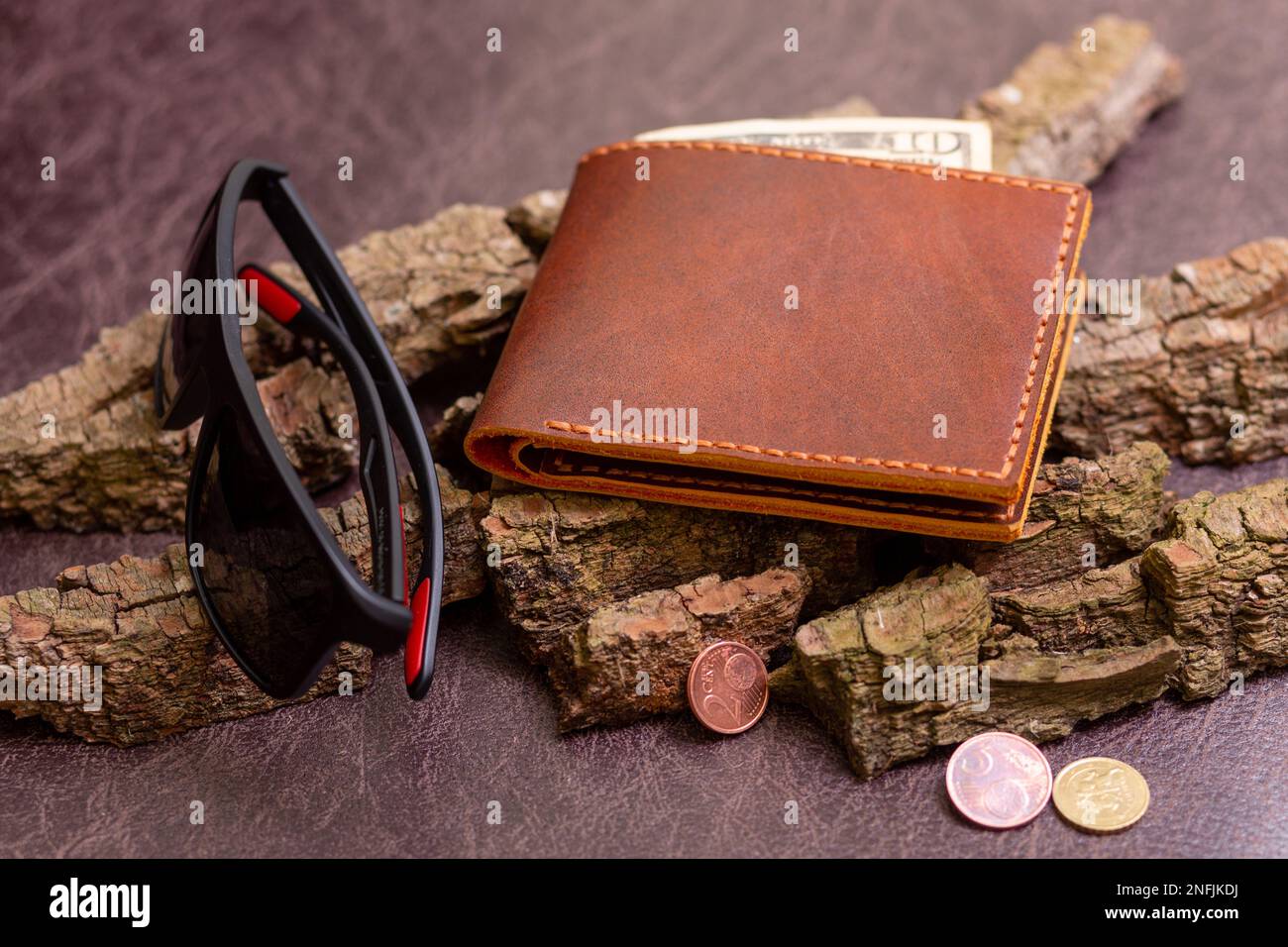 Open brown mens wallet with money and credit cards on leather background with pine bark. Stock Photo