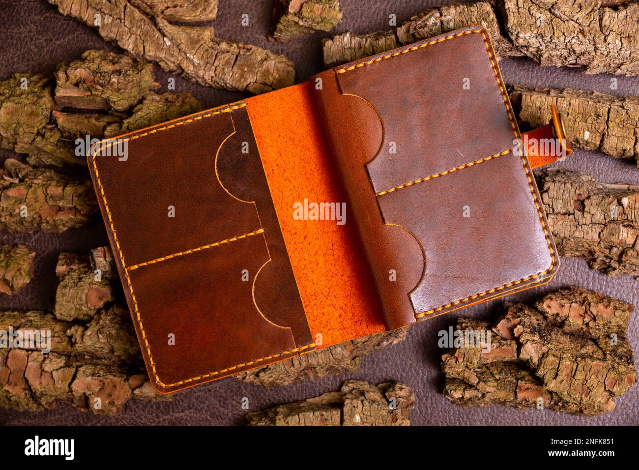 Open brown mens wallet for cash and credit cards on leather background with pine bark. Stock Photo