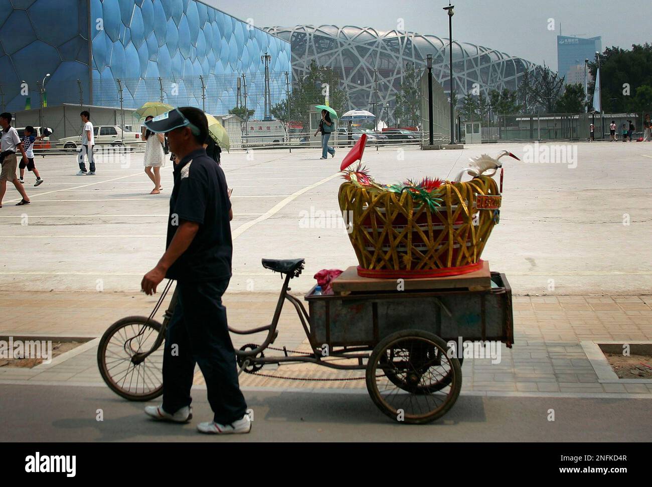 Qin Shengun walks along side his scale replica of the National Stadium,  also known as the Bird's Nest, outside of the fenced security perimeter  that surrounds the actual Bird's Nest, in Beijing,