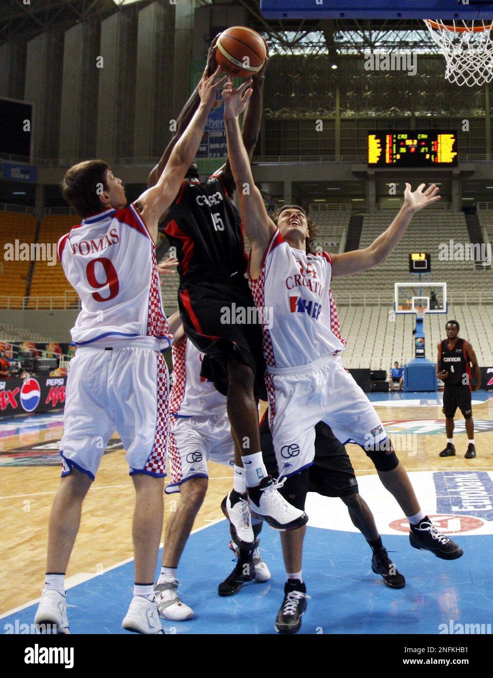 Joel Anthony of Canada, center, and Kresimir Loncar, right, Marko Tomas of  Croatia fight for the ball during a quarter-final basketball game for FIBA  Olympic qualifying tournament at the indoor Olympic arena