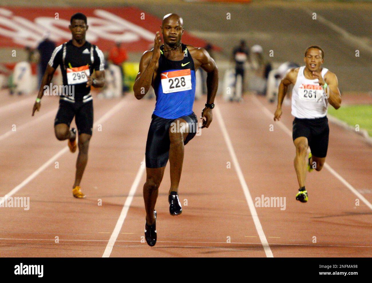 Asafa Powell, center, wins his heat, in front of Dwight Williams, left