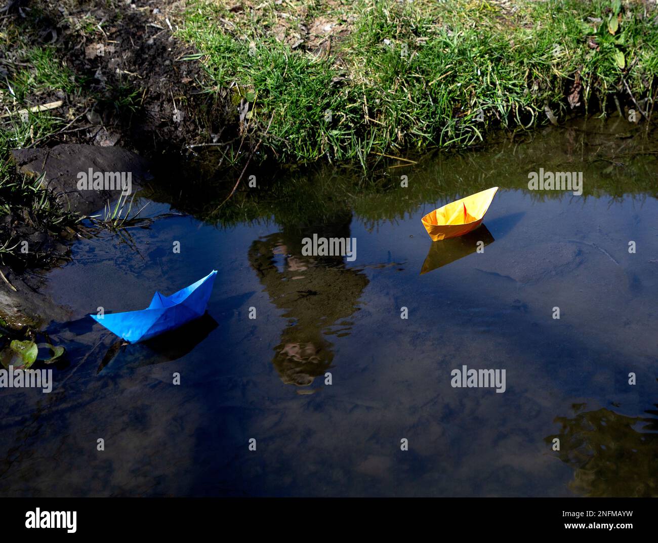 yellow and blue paper boats, origami, floating in the stream on a sunny spring day. Symbol of freedom, independence. Drawing attention to the war in U Stock Photo