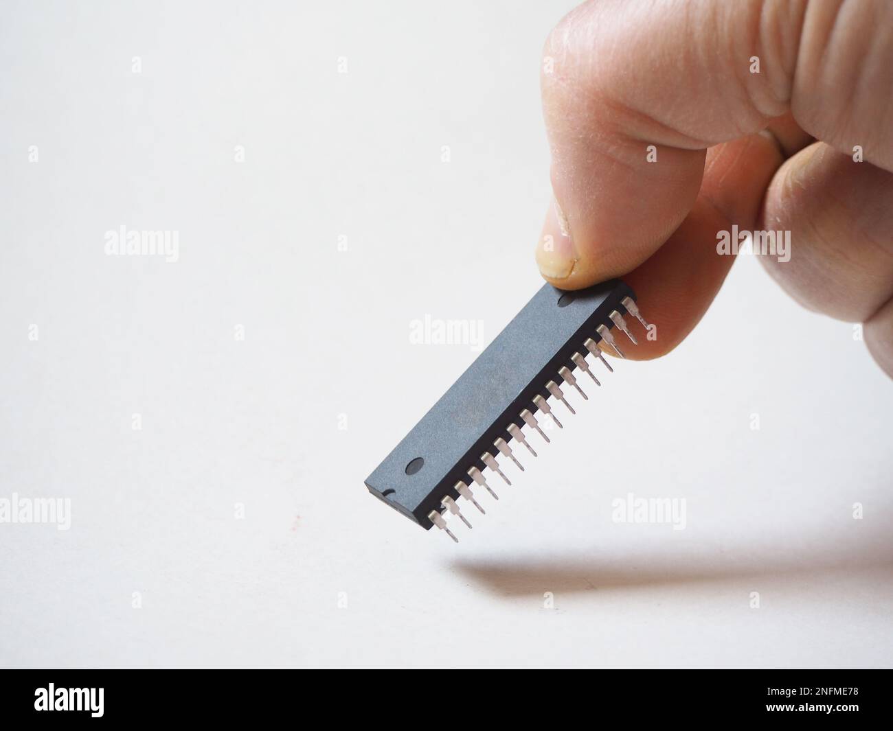 Hand holding an electronic chip with 32 pins. Isolated integrated circuit. Stock Photo