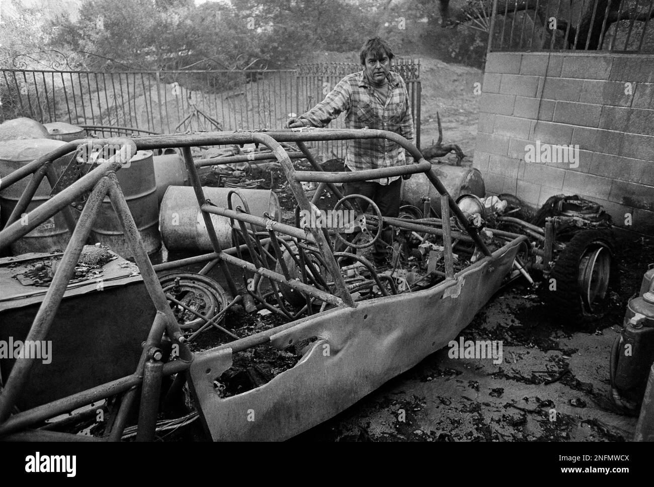 Renowned race car driver Mickey Thompson stands behind his burnedout
