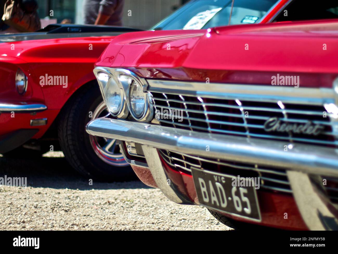 Red Chilli Chevrolet Impala Front-End View with Red and Black Ford Mustang in the Background Stock Photo