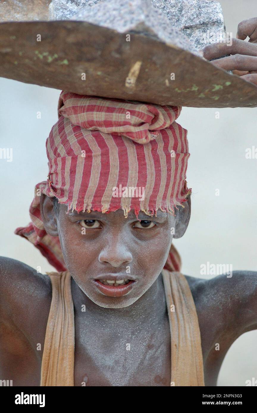 A child laborer carries stones on his head at a stone crusher on the ...