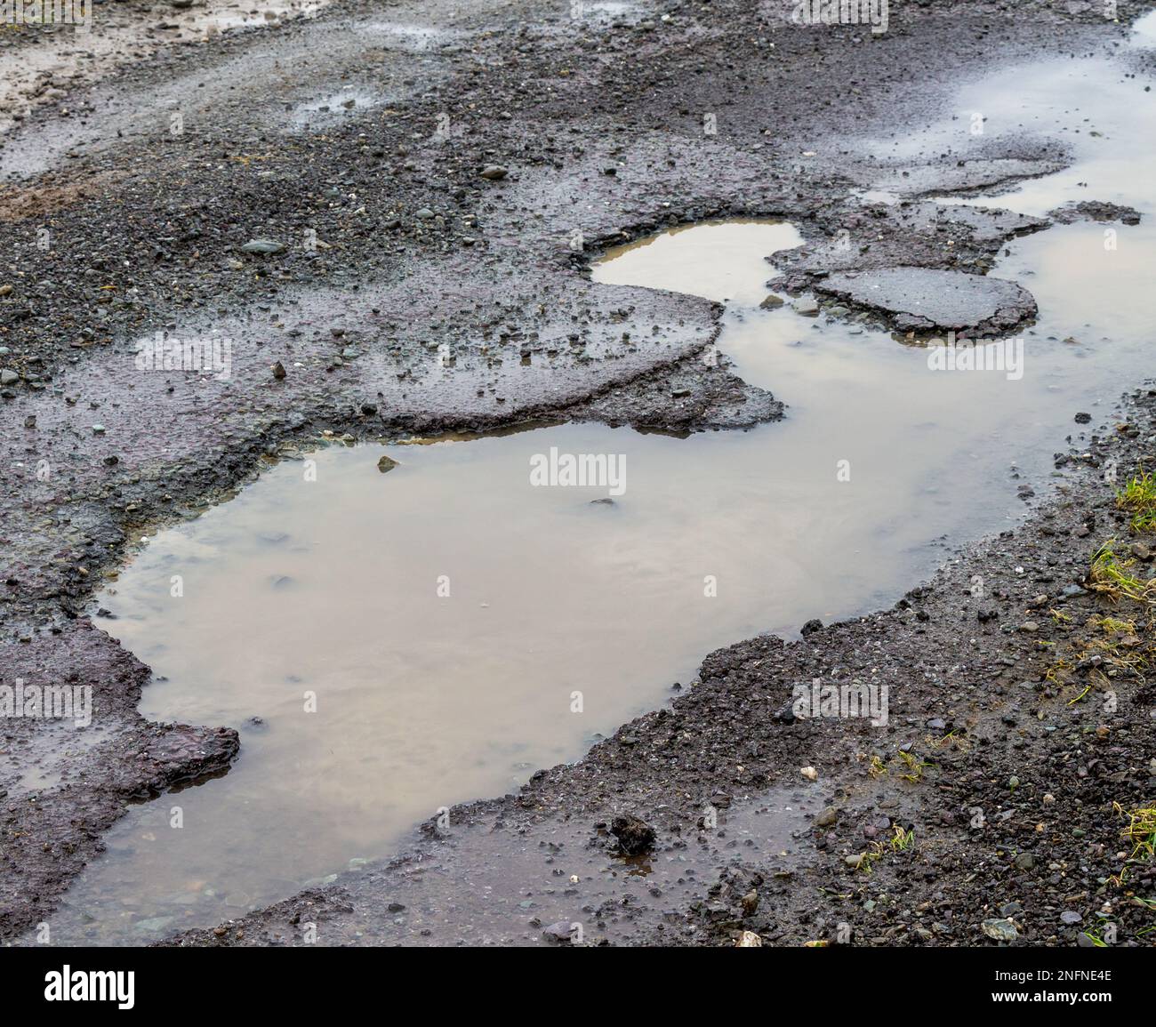 Potholes in road surface breaking up tarmac caused by winter frost and