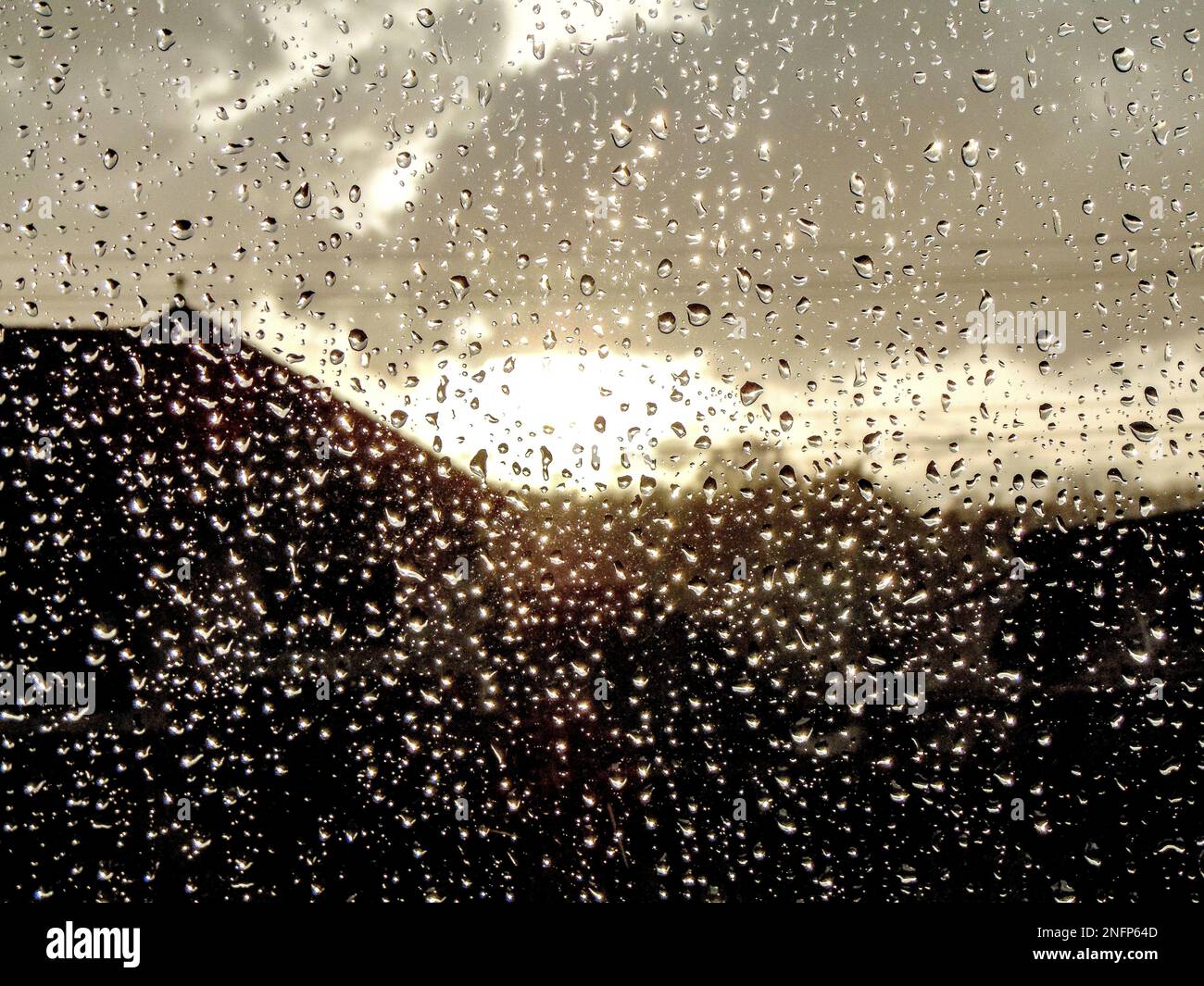 raindrops on a window and the sun coming out of the clouds Stock Photo