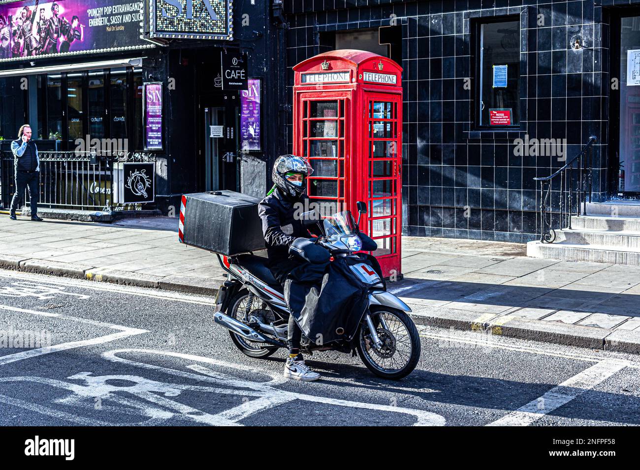 A delivery moped rider stopped on a bike lane in Soho, London, England