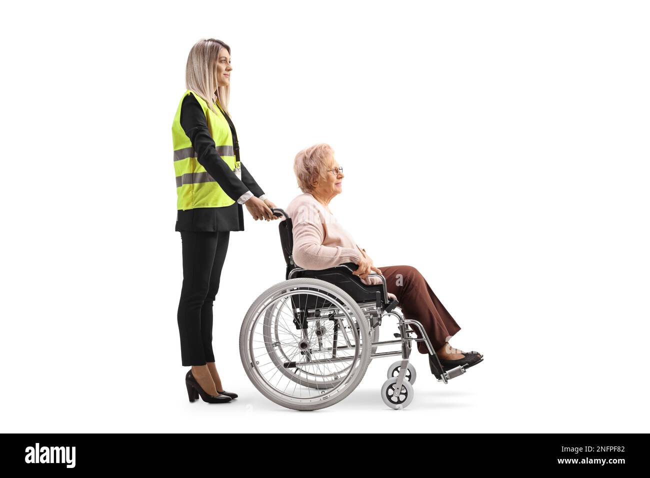 Special assitance worker standing behind a senior woman in a wheelchair isolated on white