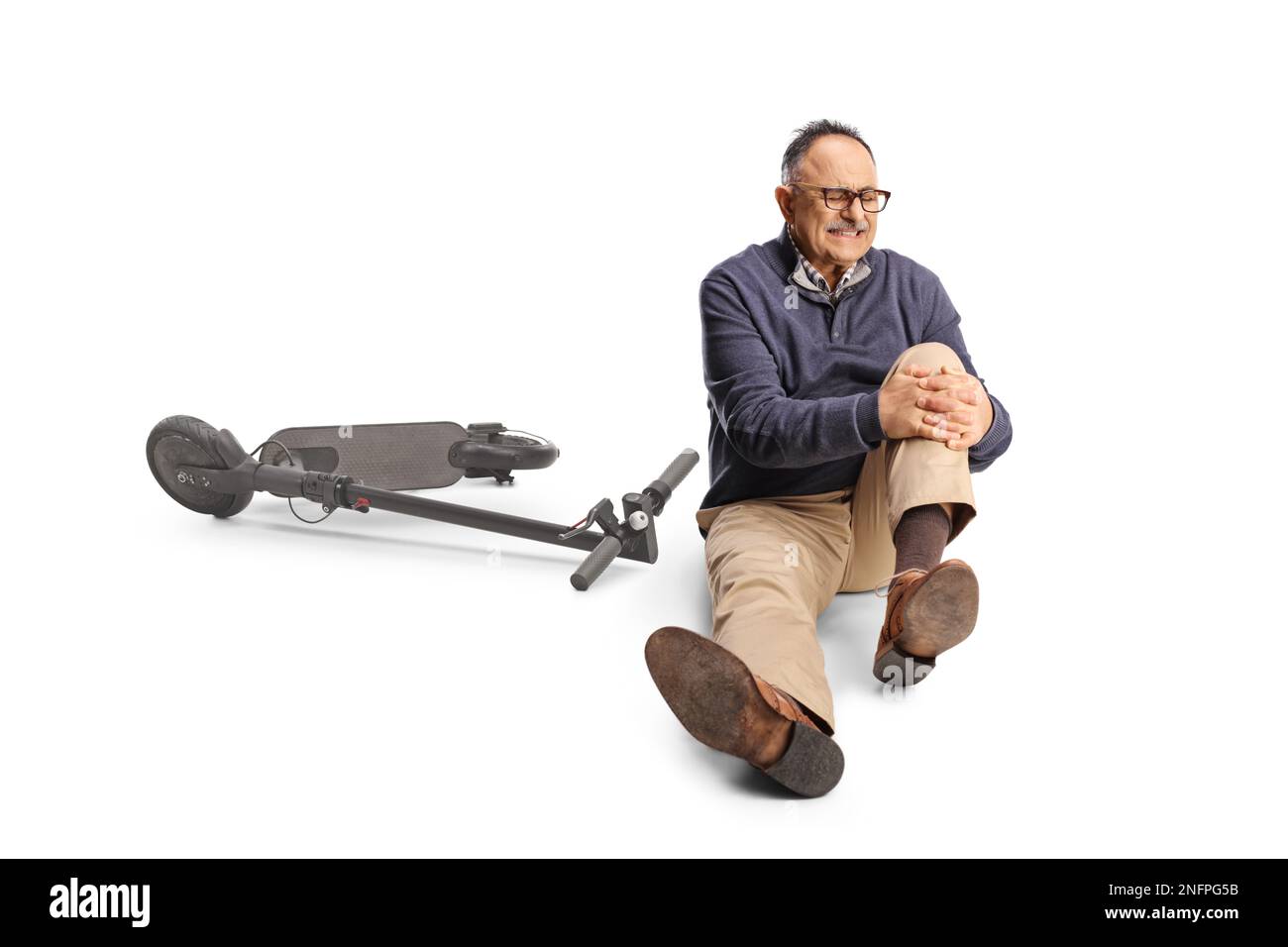 Mature man with an electric scooter holding his painful knee and sitting on the ground isolated on white background Stock Photo