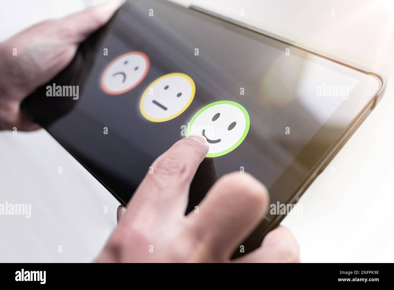 pleased person giving positive feedback by touching smiley face on digital tablet touchscreen, service quality rating concept Stock Photo