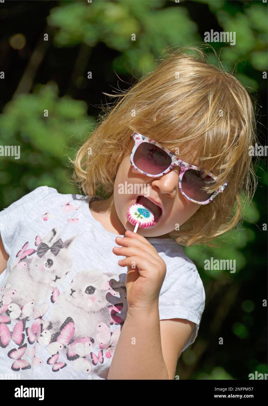 Sweet child sucking a lollipop outdoors. Portrait format Stock Photo