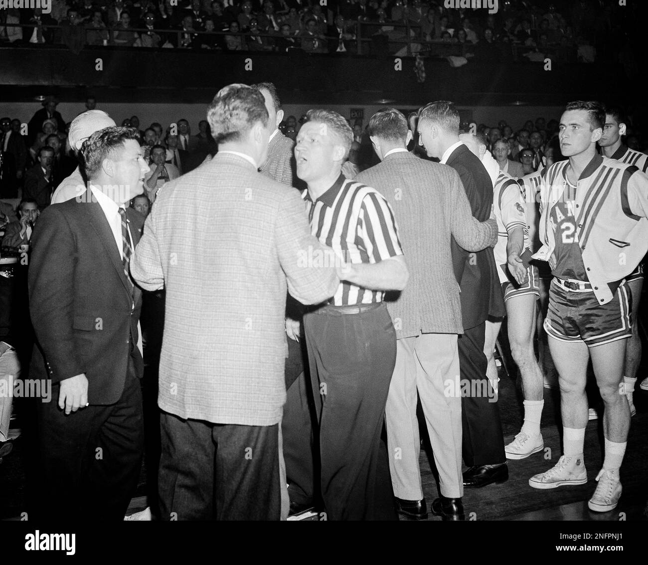 Coach Frank McGuire, for North Carolina, is restrained by referee John  Conway after an exchange of words with Kansas University Coach Dick Harp  following a tussle on the floor between Wilt Chamberlain,