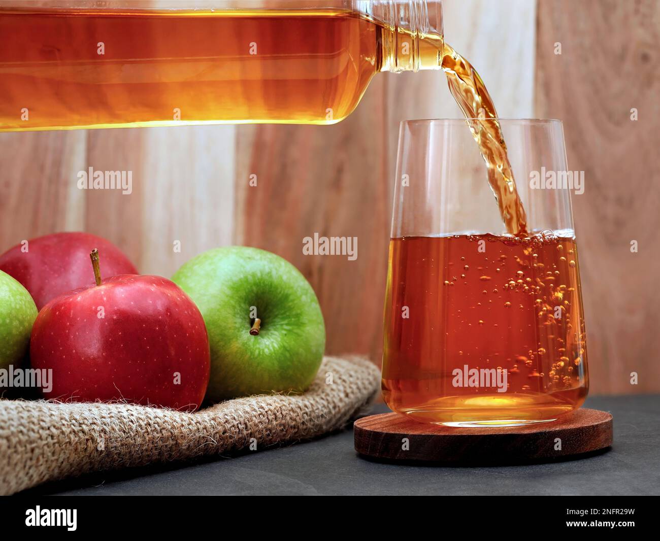 Fresh apple juice pours from a bottle into a glass on the table, Refreshing fruity juice Stock Photo
