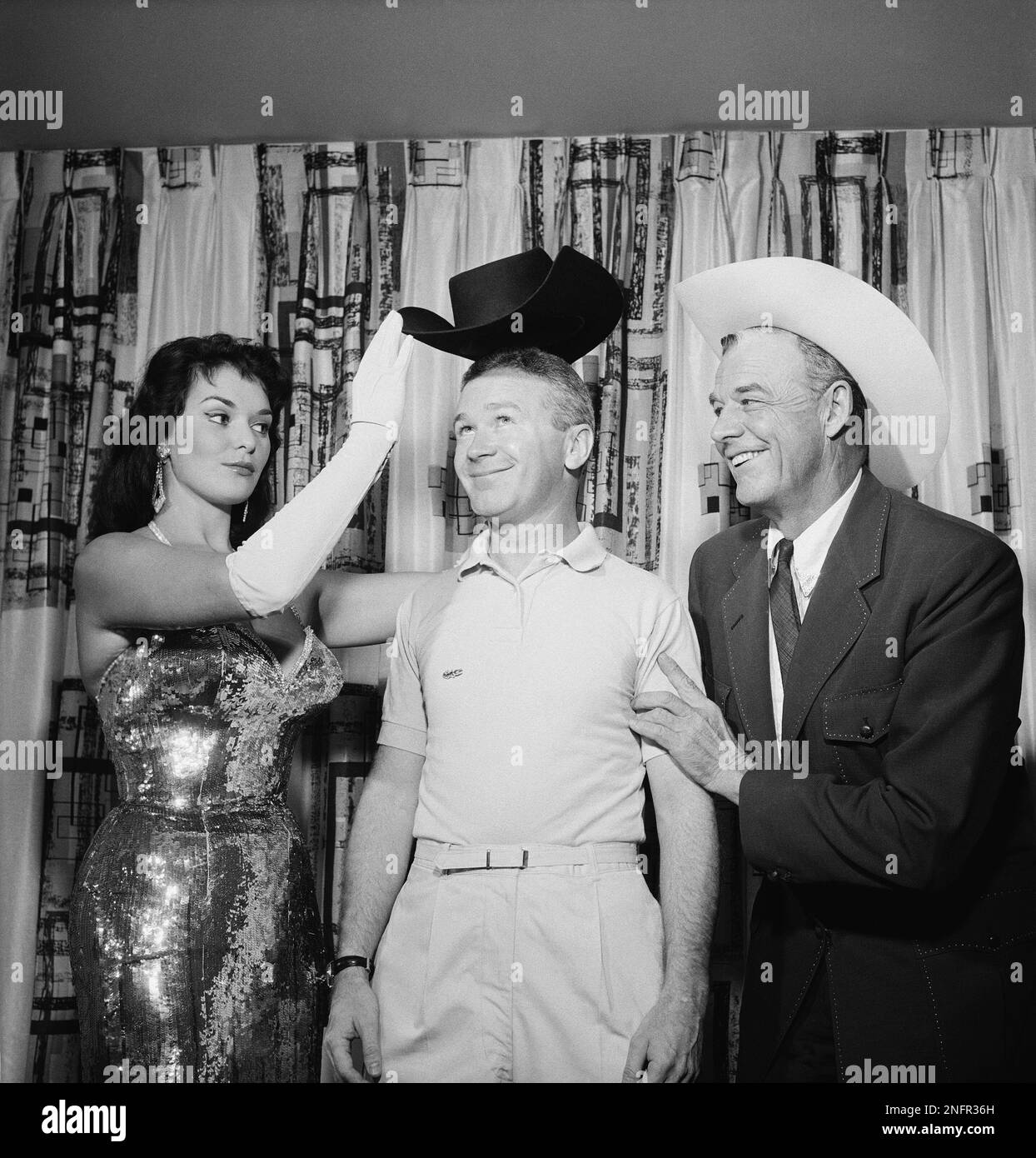 Comedian Red Buttons is presented a western hat by Rex Bell, Lt. Gov. of  Nev., left, and Felecia Atkins, Tropicana showgirl in Las Vegas, before his  opening Oct. 1, 1958 at the