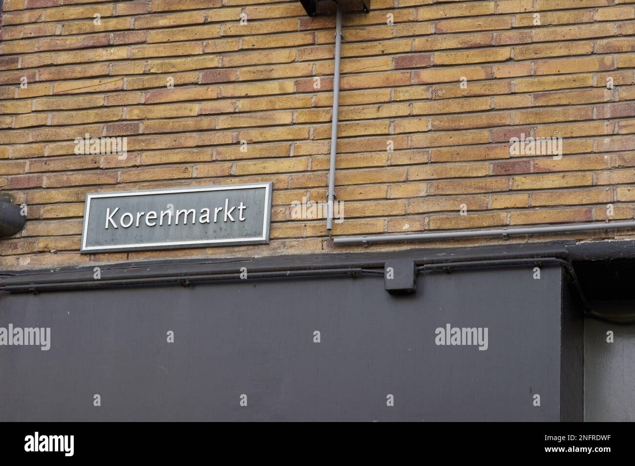 Blue street name sign of Korenmarkt on a brick stone wall in Arnhem in