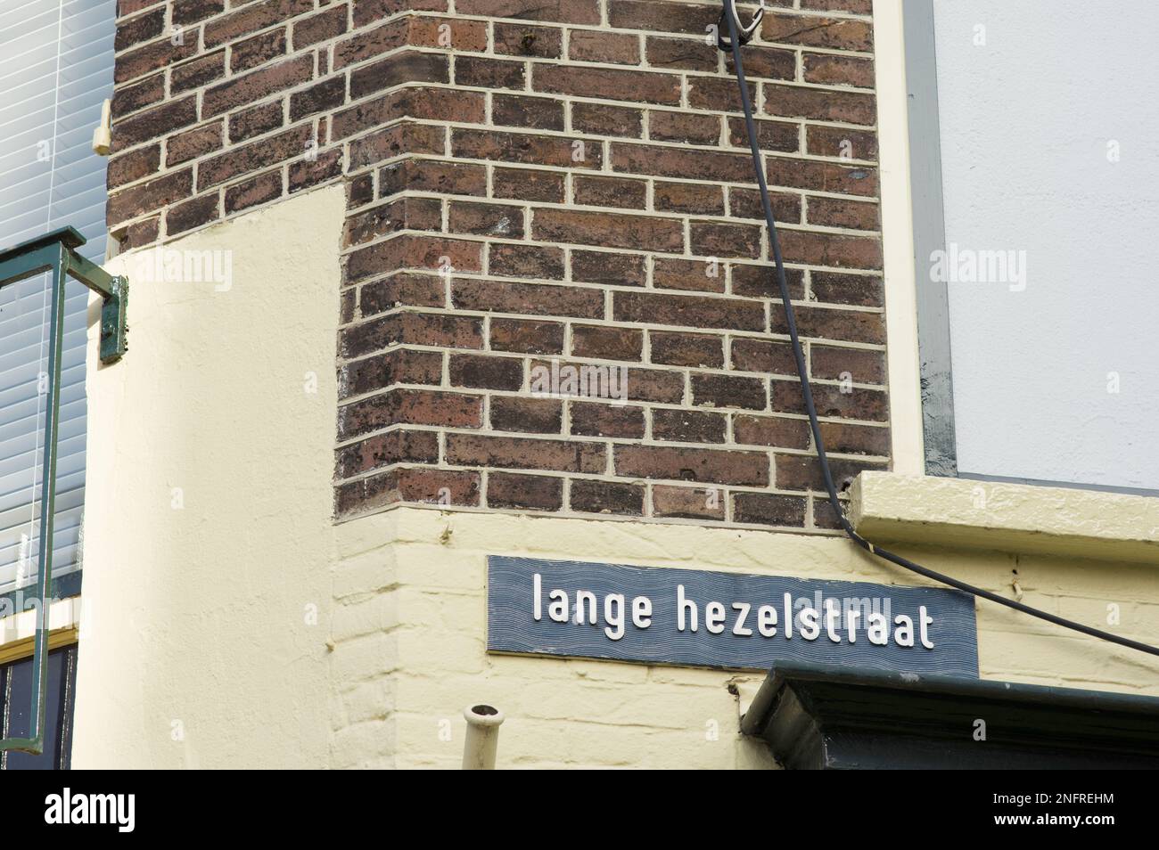 Blue street name sign of Lange Hezelstraat on a brown stone wall in