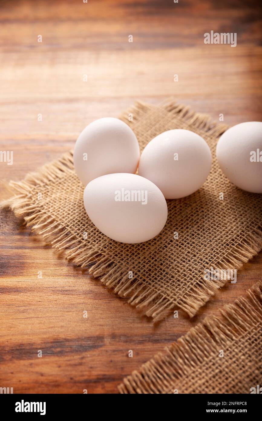 Many white chicken eggs on rustic wooden table. Very popular nutritious and economic food product. Stock Photo