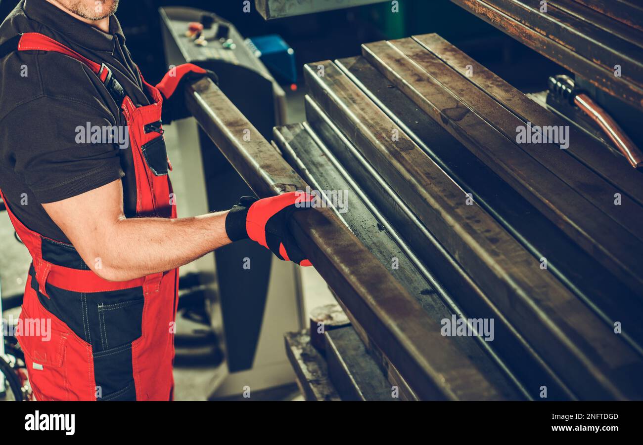 Metalworking Industry Worker Arranging Metal Square Tubes in the Workshop. Industrial Production Theme. Stock Photo