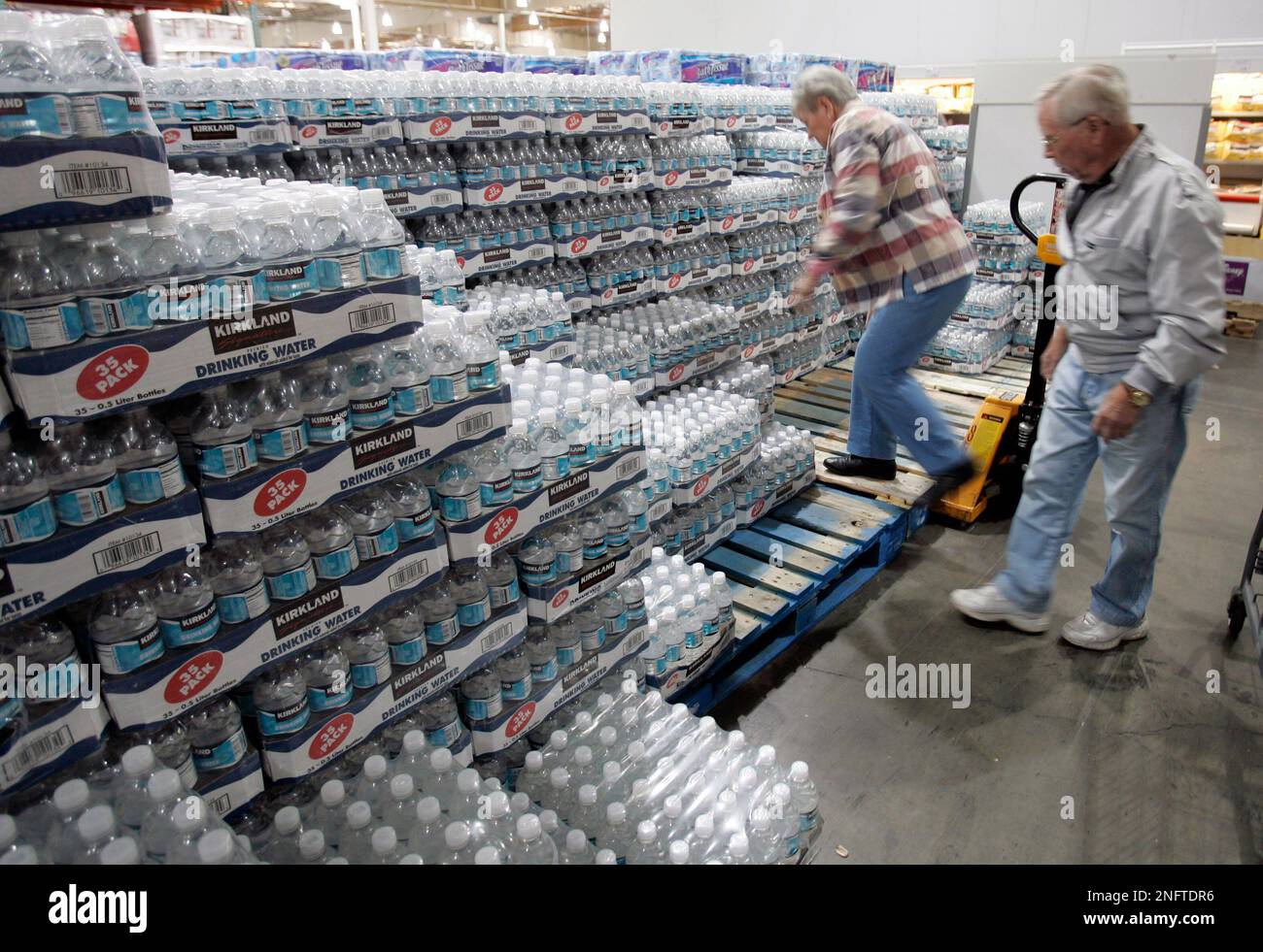 Costco customers pick out a case of drinking water from the Costco