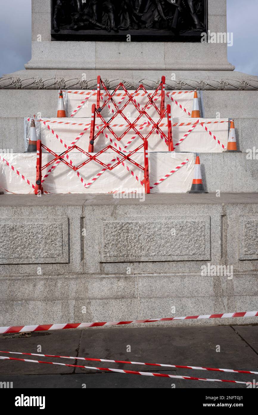 Hazard tape covers repairs to granite stonework of the plinth to Nelson's Column in Trafalgar Square, on 17th February 2023, in London, England. Stock Photo