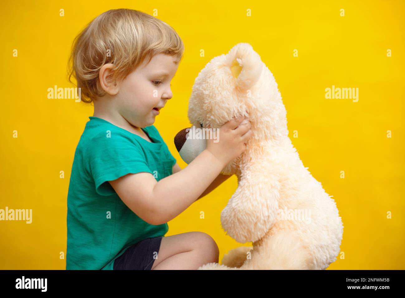Little boy hugging teddy bear toy on yellow background Stock Photo - Alamy