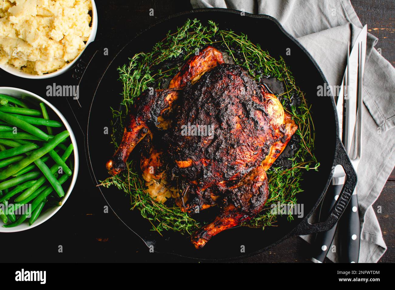 Apple Butter Roasted Chicken Served with Vegetable Side Dishes: Roast chicken in a cast iron pan with mashed potatoes and green beans Stock Photo