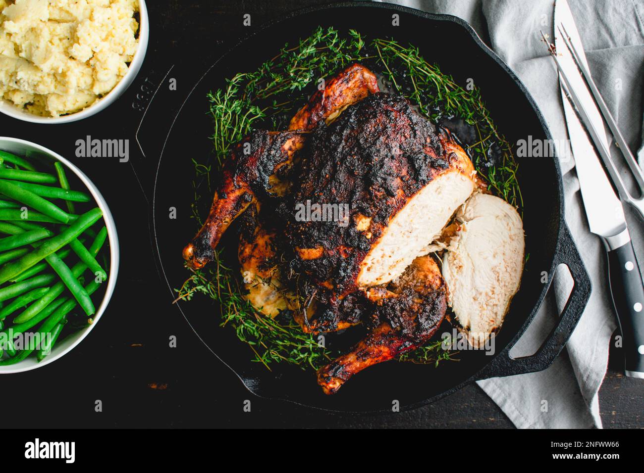 Sliced Apple Butter Roasted Chicken with a Carving Knife and Fork: Roast chicken in a cast iron pan with mashed potatoes and green beans Stock Photo