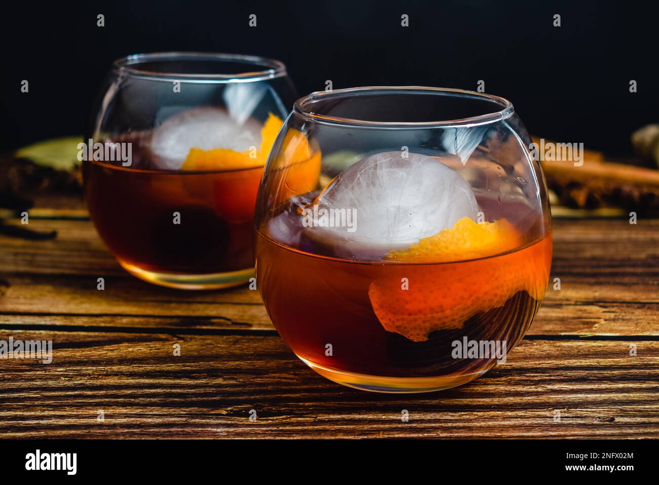 https://c8.alamy.com/comp/2NFX02M/spiced-old-fashioned-cocktail-in-a-balloon-glass-with-an-ice-sphere-bourbon-whiskey-cocktail-with-an-orange-peel-and-maraschino-cherry-garnish-2NFX02M.jpg