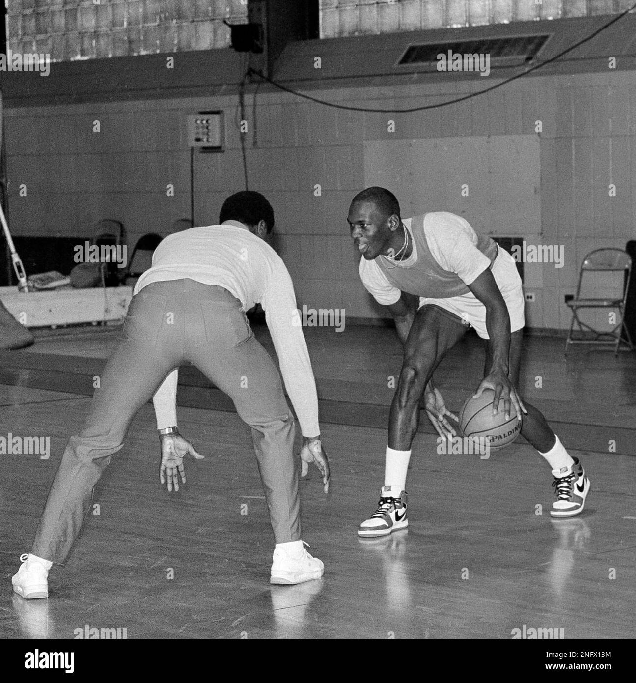 Chicago Bulls' Michael Jordan looks at assistant coach Fred Carter as he  moves the ball between his legs during a team workout in Chicago, Jan. 25,  1985. (AP Photo/Charles Bennett Stock Photo -