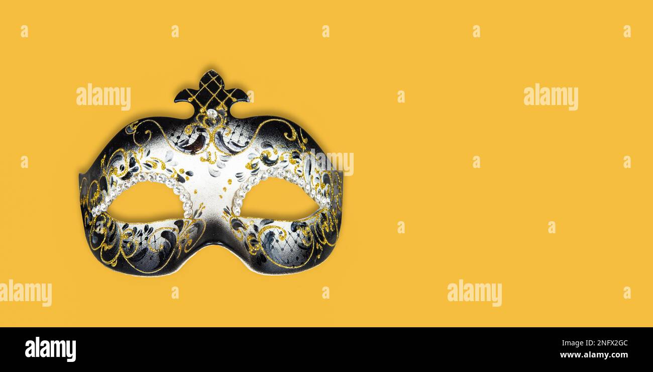 Carnival background with Venetian mask isolated on yellow background. Stock Photo