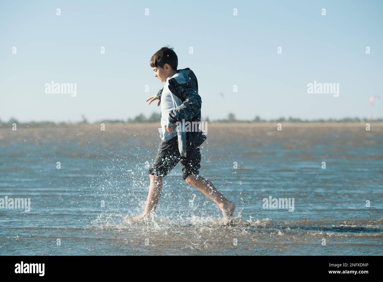 A young boy playing and splashing around on a seashore Stock Photo - Alamy