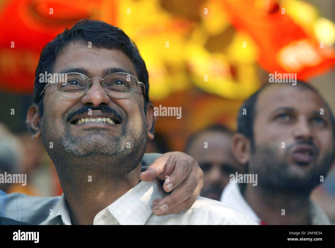 Onlookers watch share prices on a screen on the facade of the Bombay