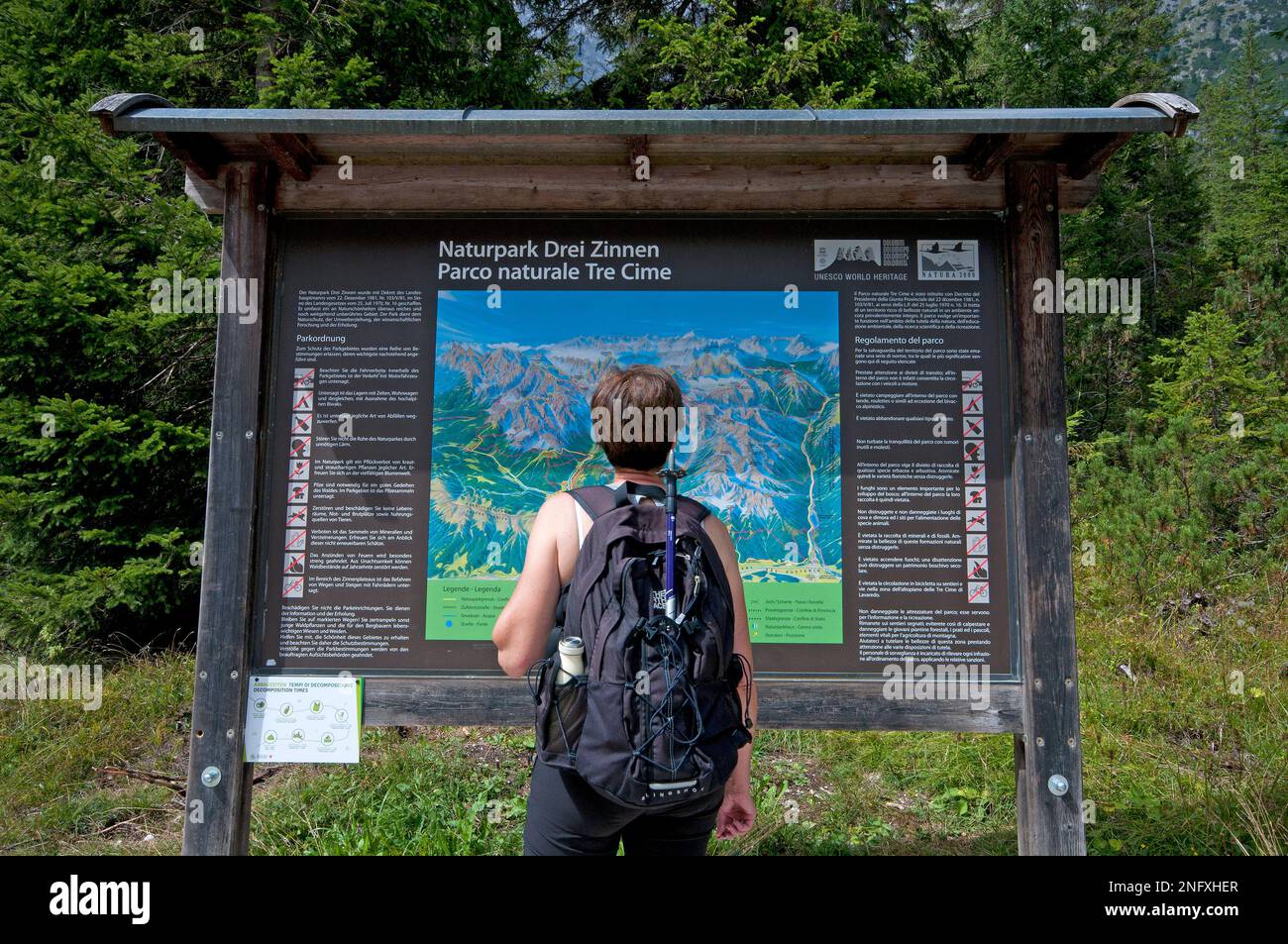Trekker checking a map board of Tre Cime Nature Park,  Fiscalina Valley,Trentino-Alto Adige, Italy Stock Photo