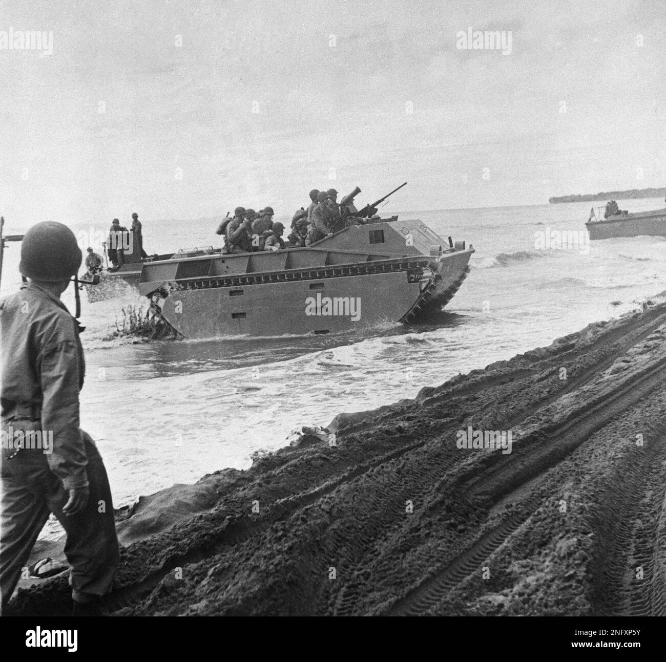 U.S. Marines ride an amphibious tank as it reaches shore and starts to ...