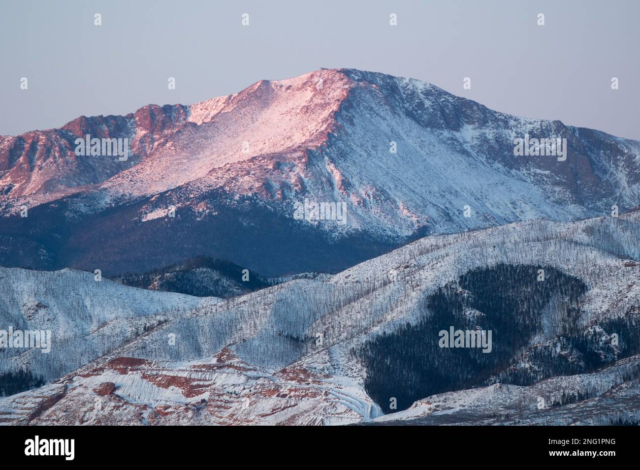 Alpenglow and sunrise on PIkes Peak, after a winter storm.  Pikes Peak is 14, 100 feet high, and towers over Colorado Springs, Colorado. Stock Photo