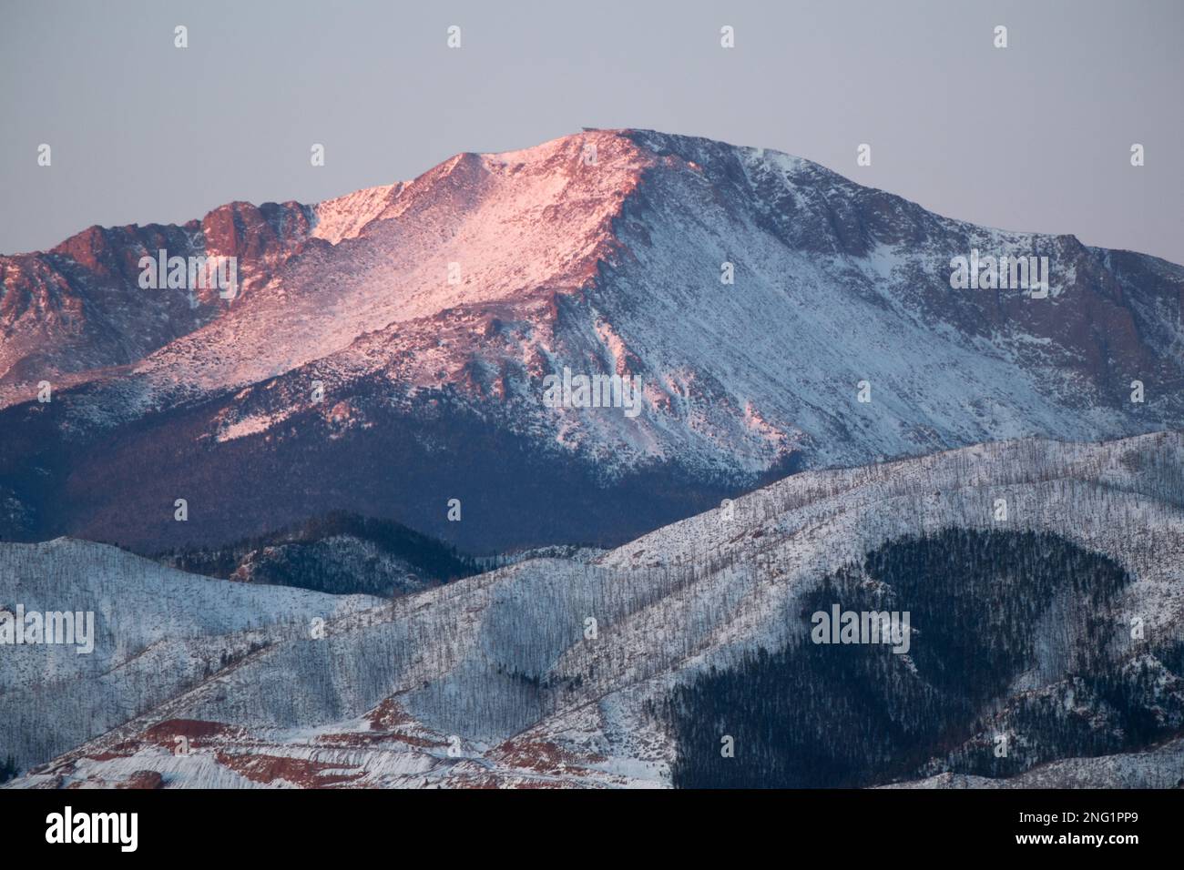 Alpenglow and sunrise on PIkes Peak, after a winter storm.  Pikes Peak is 14, 100 feet high, and towers over Colorado Springs, Colorado. Stock Photo