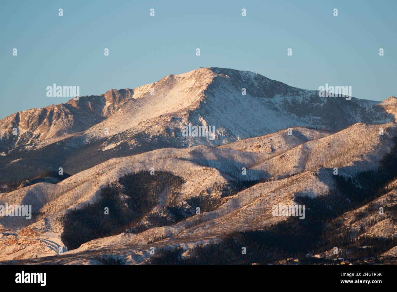 Alpenglow and sunrise on PIkes Peak, after a winter storm.  Pikes Peak is 14, 100 feet high, and towers over Colorado Springs, Colorado. Stock Photo