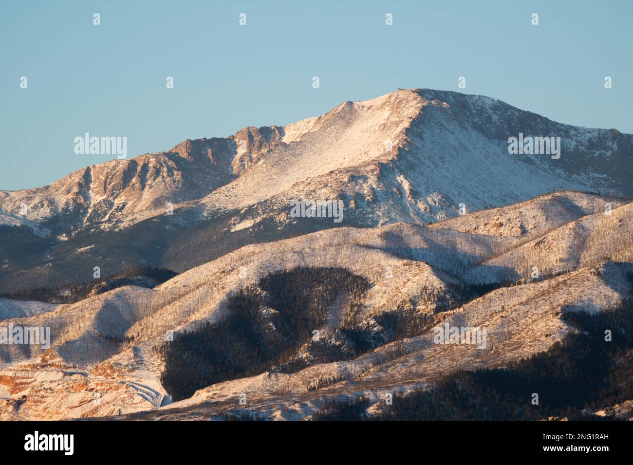 Alpenglow and sunrise on PIkes Peak, after a winter storm.  Pikes Peak is 14, 100 feet high, and towers over Colorado Springs, Colorado. Stock Photo