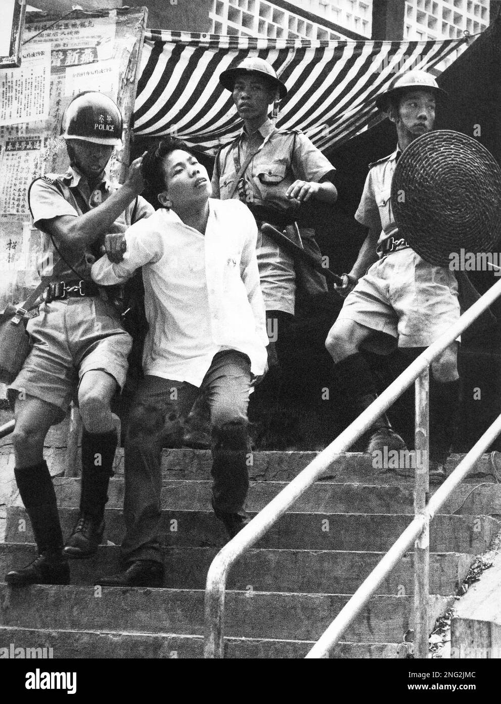 A policeman uses armlock and hairhold to force a young demonstrator