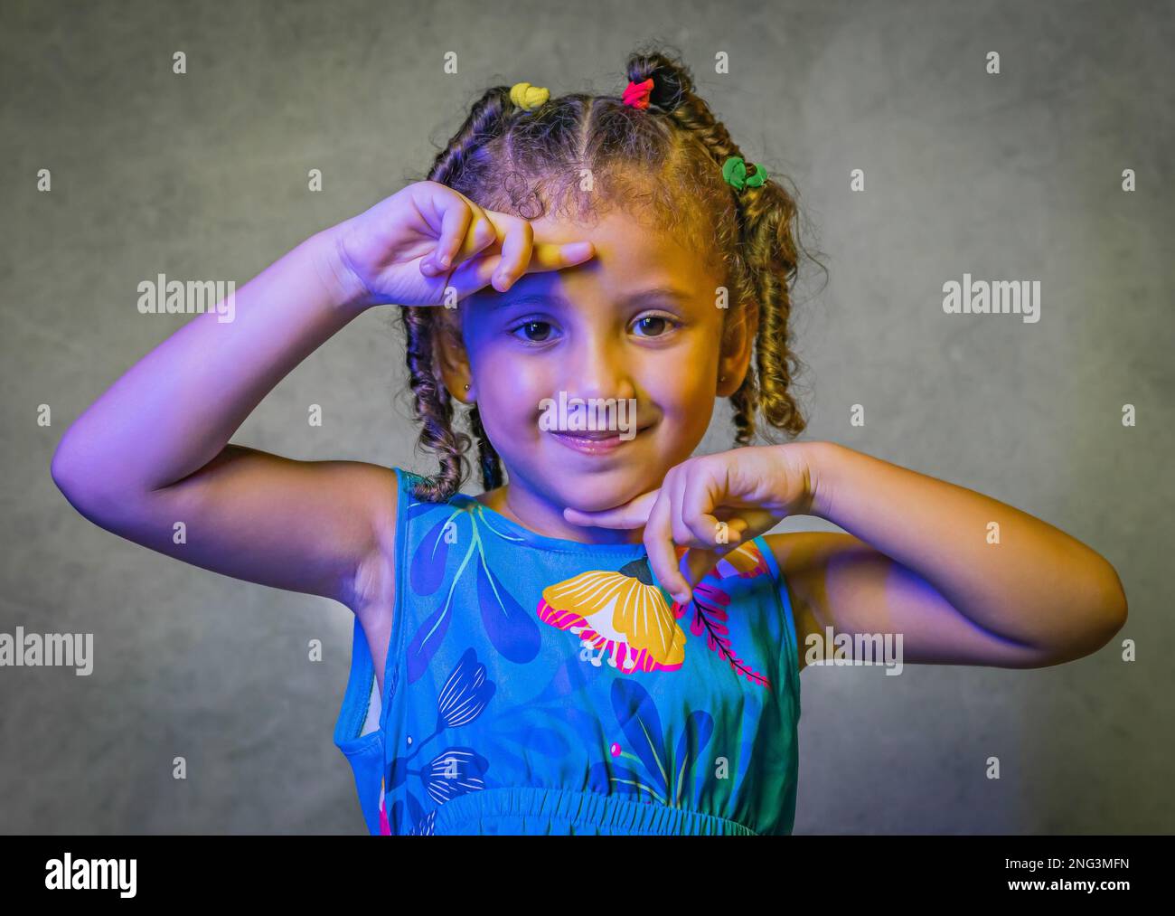 Studio portrait of beautiful little girl in beautiful blue dress on purple background, brazilian girl smiling, giving kisses and making funny faces Stock Photo