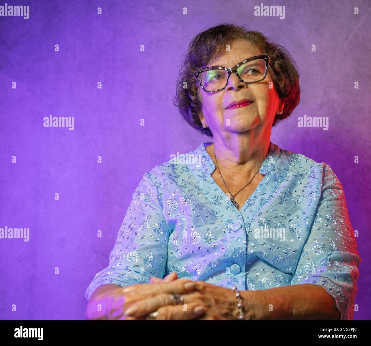 Portrait of an old lady with blue dress and purple lighting Stock Photo
