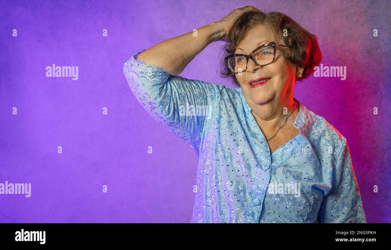 Portrait of an old lady with blue dress and purple lighting Stock Photo