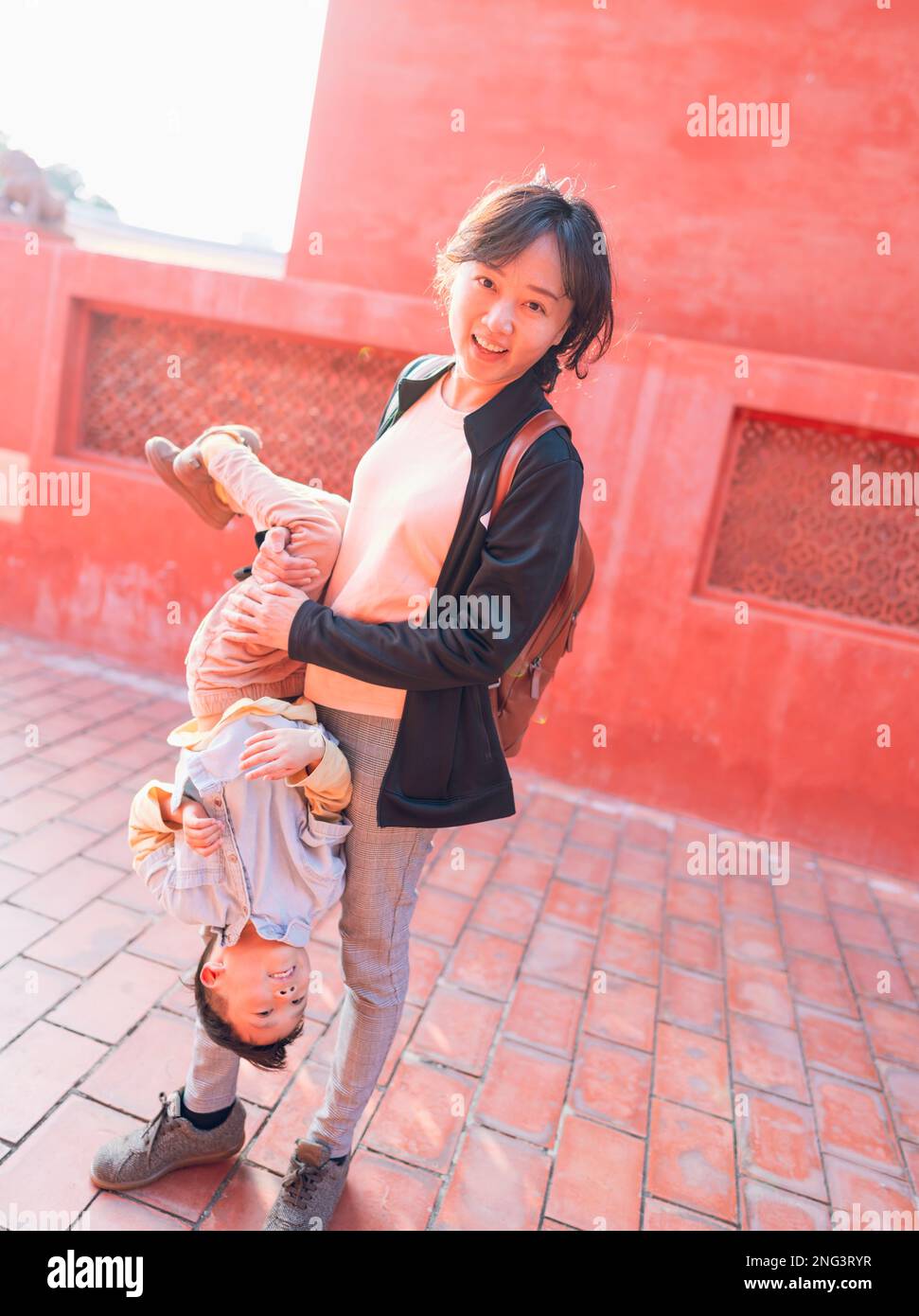 Mother and son play in front of a read background. The photo was taken in the Confucius Temple in Tainan Taiwan. Stock Photo