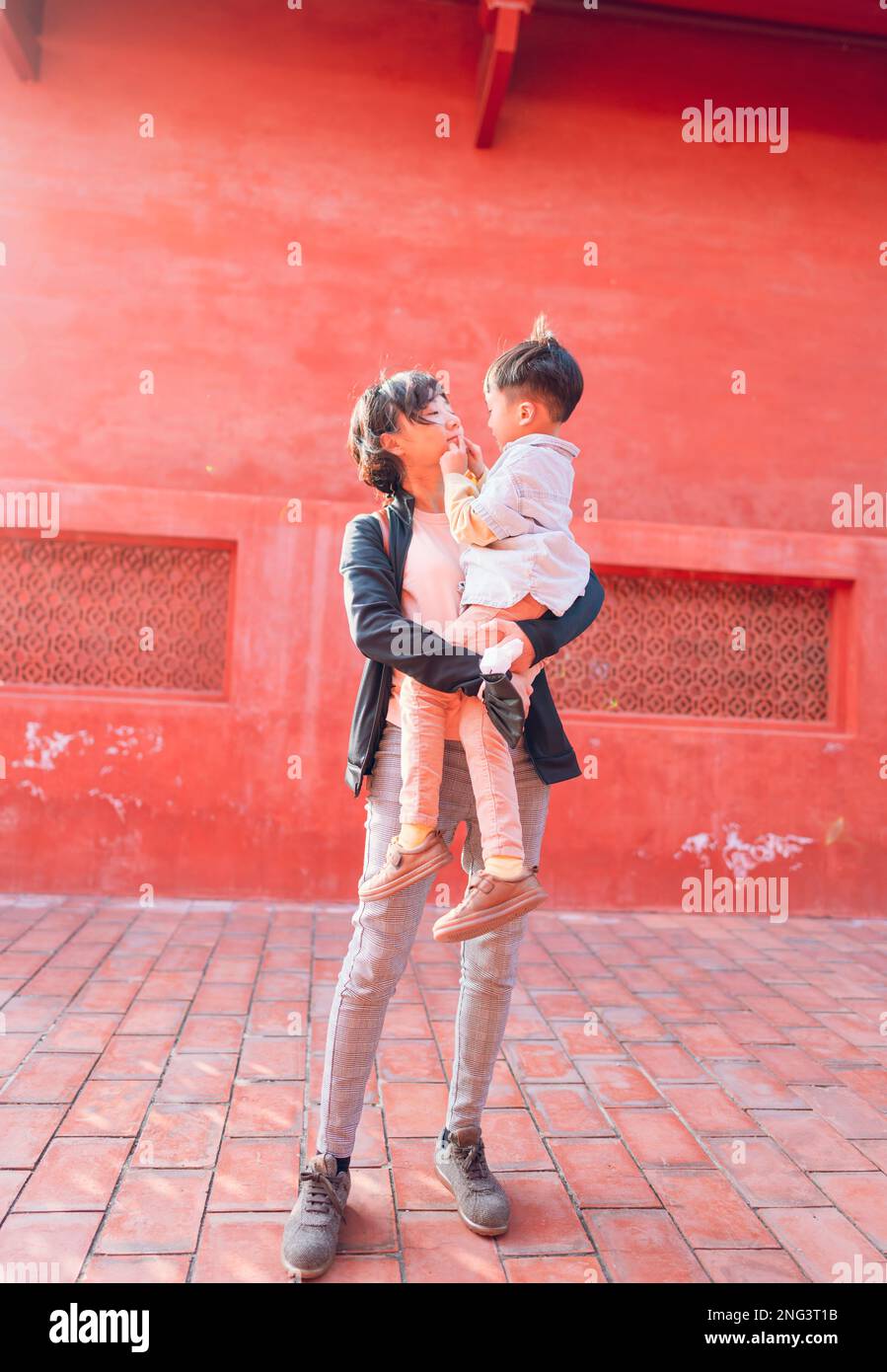 Mother and son with red background. The photo was taken in the Confucius Temple in Tainan Taiwan. Stock Photo