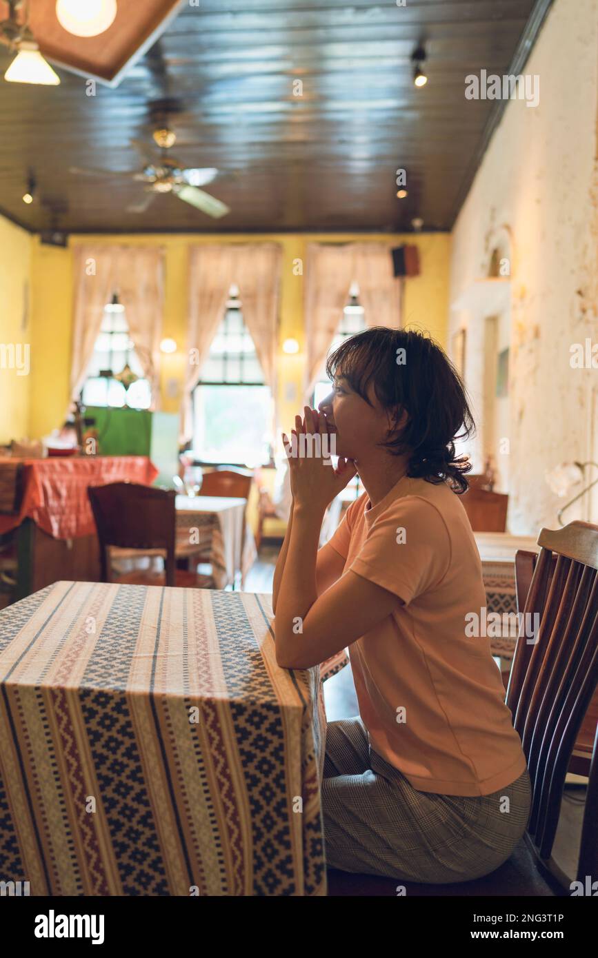 A woman looks at her front with smile. It was in a retro-style cafe in southern Taiwan. Stock Photo