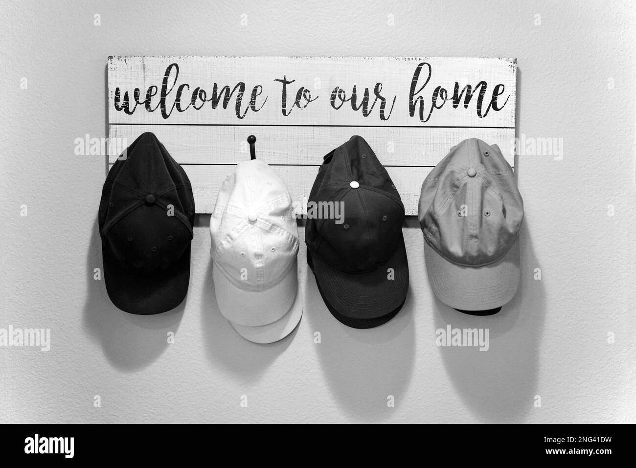 Caps hanging on a wooden hat rack with welcome greeting on wall Stock Photo