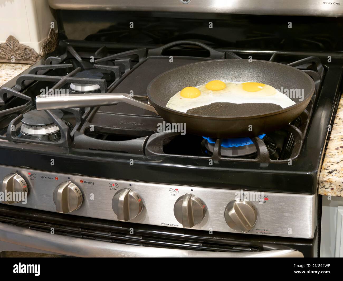 Eggs frying in a skillet or frying pan for cooking on a gas stove or stovetop in a home in the USA. Stock Photo